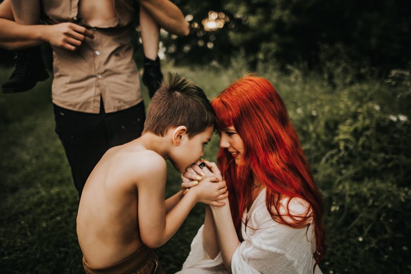 a beautiful red haired mother with family in a green field