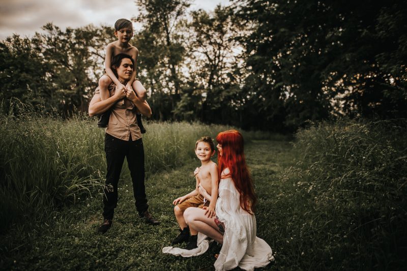 a beautiful red haired mother with family in a green field