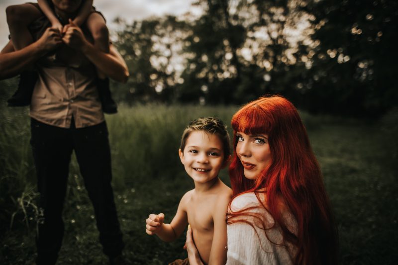 a beautiful red haired mother with family in a green field