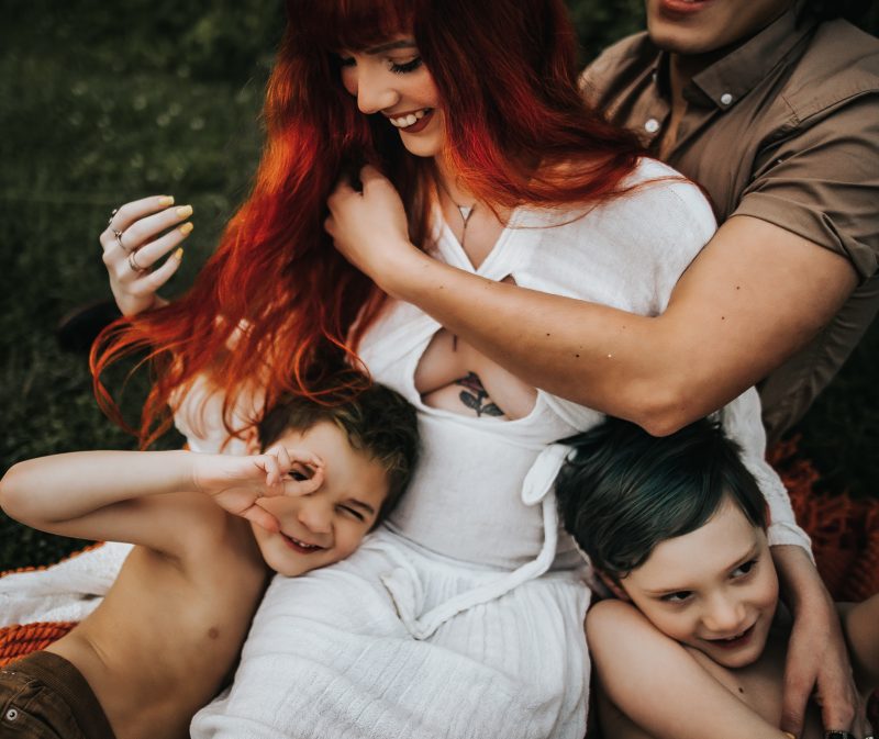a beautiful red haired mother with family in a green field
