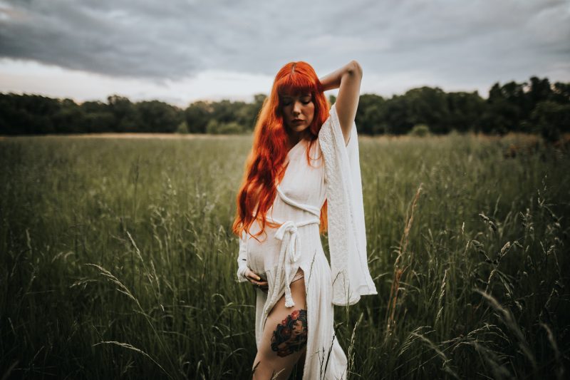 a beautiful red haired mother with family in a green field