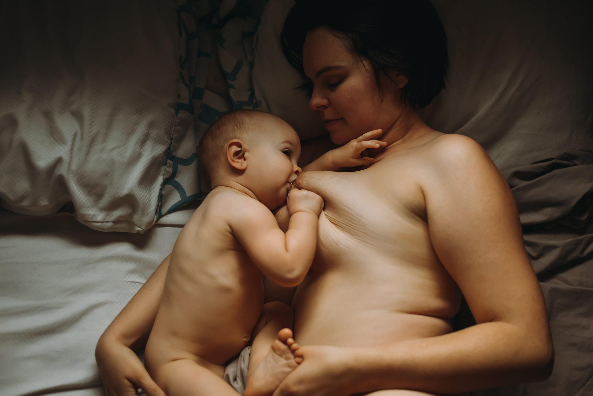mother and baby breastfeeding in bed