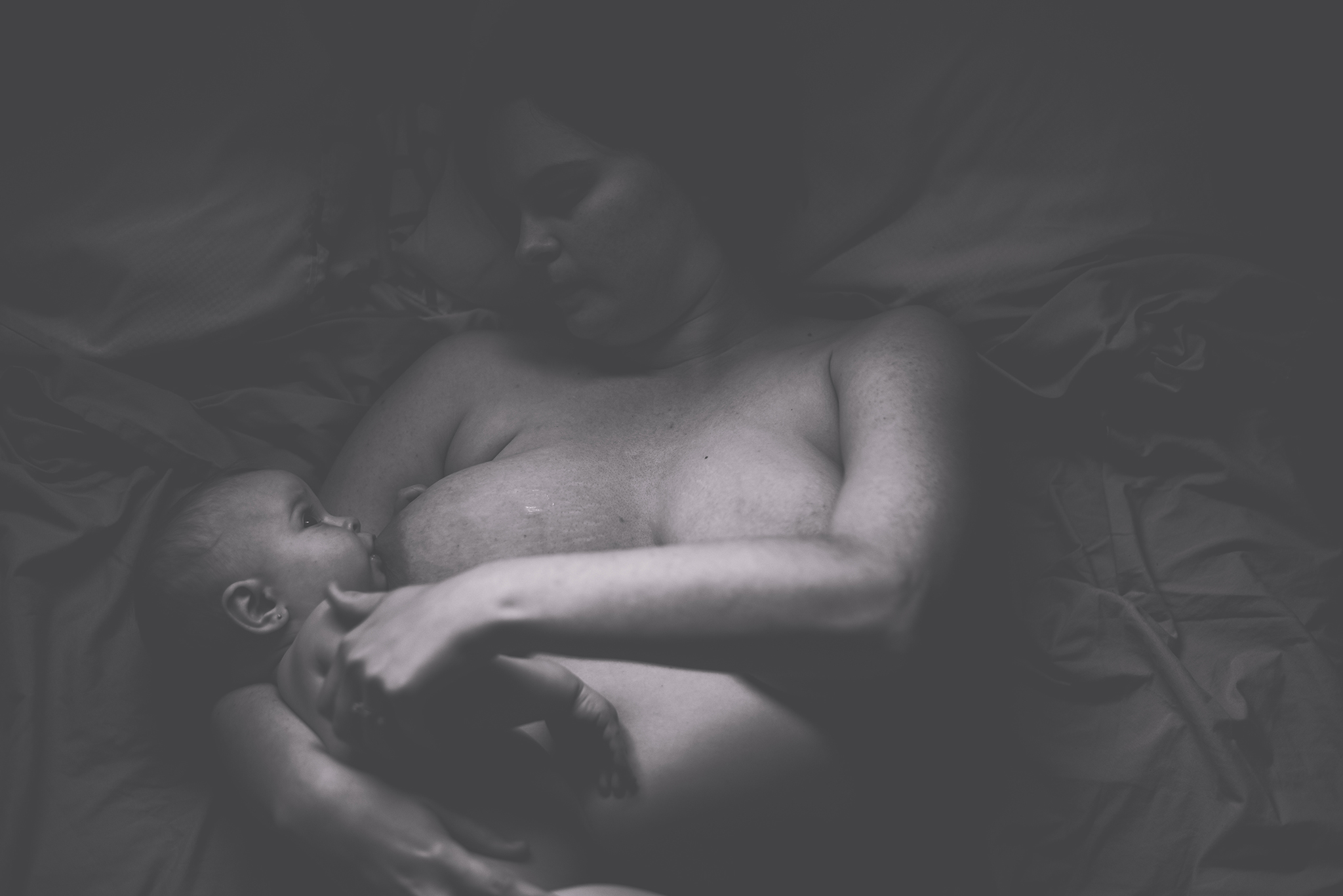mother and baby breastfeeding in bed
